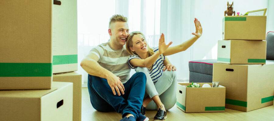 Casal sentado no chão admirando casa com objetos em volta